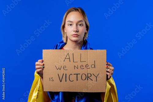 Ukrainian woman with cardboard All we need is victory on blue background. photo