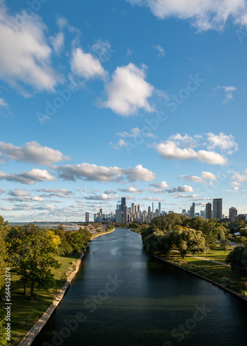 Aerial view of the downtown Chicago city skyline from above the South Lagoon canal as rowing boats and a standup paddleboard make their way through the calm water on a sunny blue sky day.