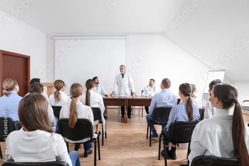 Senior doctor giving lecture near projection screen in conference room