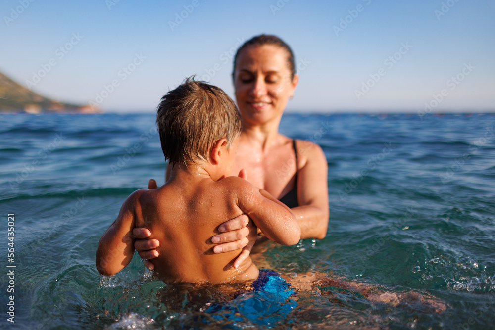 Cheerful mother plays with her son in the sea Cheerful mother plays with her son in the sea