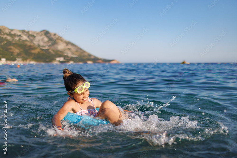 Cheerful girl sits in an inflatable circle and splashes with water in the sea Cheerful girl sits in an inflatable circle and splashes with water in the sea