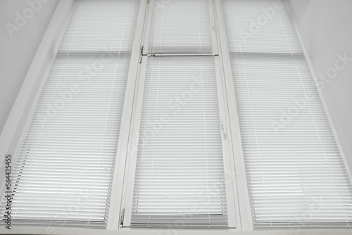 Stylish window with horizontal blinds in room, low angle view
