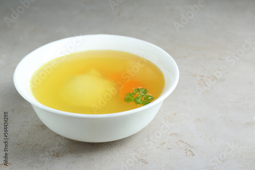 Delicious chicken bouillon with parsley on light grey textured table. Space for text
