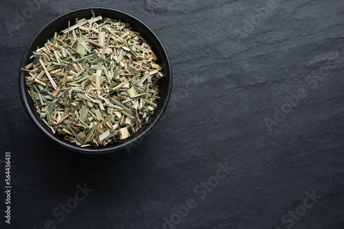 Bowl with aromatic dried lemongrass on black table, top view. Space for text