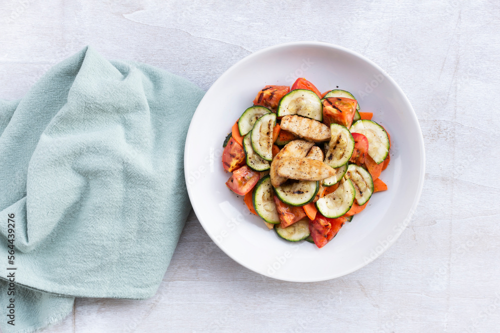Healthy food grilled chicken salad has zucchini carrot tomato in white bowl on wood background. Healthy food grilled chicken salad has zucchini carrot tomato in white bowl on wood background.