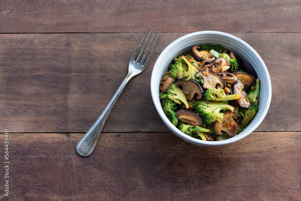 Healthy vegetarian food stir fried broccoli mushroom in bowl on wood table. Healthy vegetarian food stir fried broccoli mushroom in bowl on wood table.