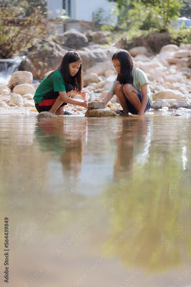 Two asian siblings playing sand nearing the river together with fun. Outdoor activity for children on vacation. Two asian siblings playing sand nearing the river together with fun. Outdoor activity for children on vacation.