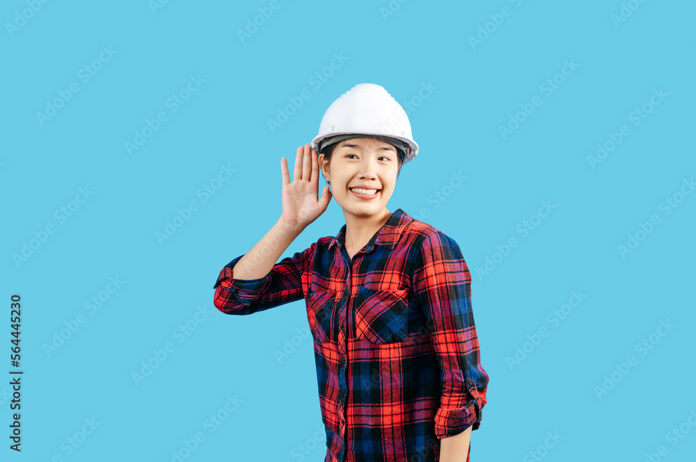 Young female engineer hand over ear to making hear gesture Young female engineer hand over ear to making hear gesture