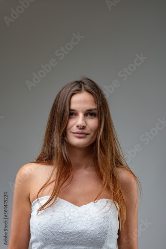 Attractive young woman in white dress, smiling confidently