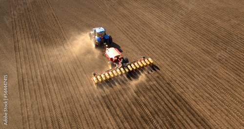 Obraz na płótnie Tractor with seeder on field drone view