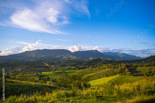 Mountain meadow in morning light. countryside springtime landscape with valley. Clouds on a bright blue sky