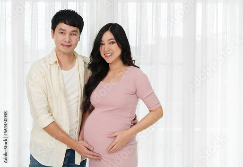 married couple is expecting baby. man embraces his pregnant wife on window background