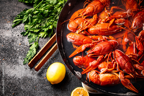 Boiled crayfish in a pot with parsley and lemon.  photo