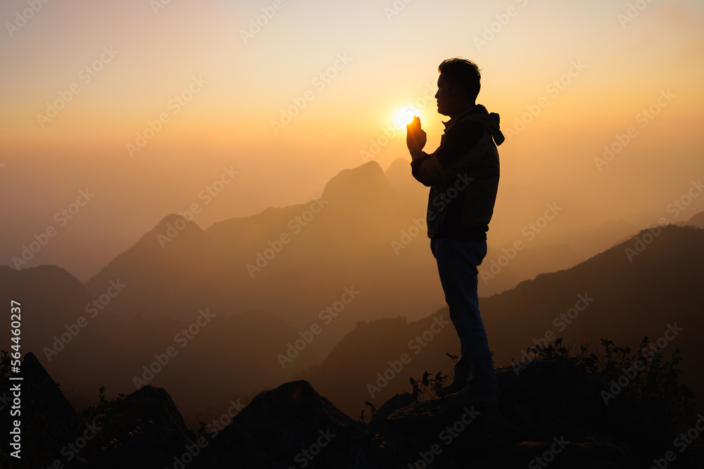 silhouette of a man is praying to god on the mountain. praying hands, pay respect.
