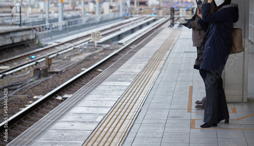 朝の名古屋駅のホームで電車待ちの女性と男性の姿