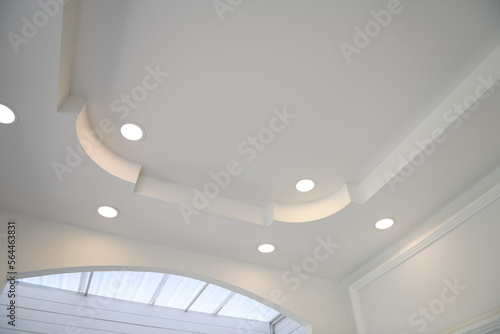 Stretch ceiling white and complex shape. ceiling with halogen spots lamps and drywall construction in empty room in exhibition hall or house.