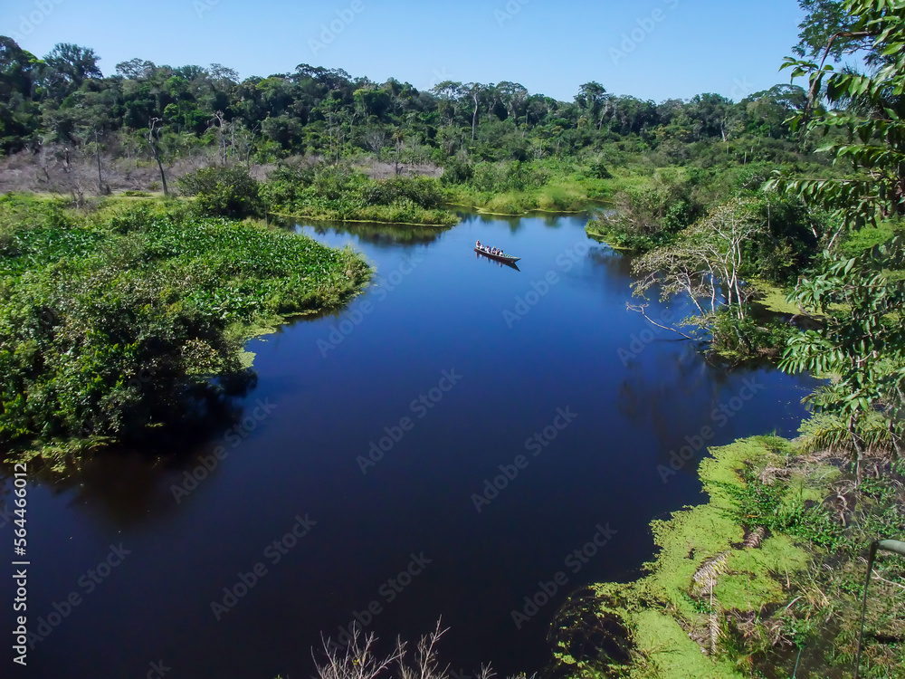 Aerial View of canoe boat in the middle of the Amazon River with lush tropical rainforest vegetation 