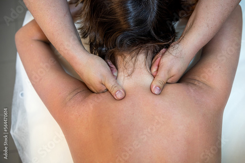 client receiving physical therapy treatment from female masseur on shoulders and back in  spa