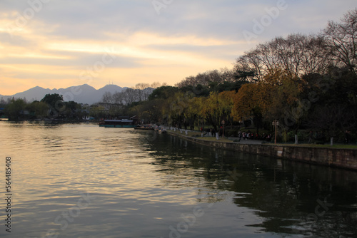 A calm seascape with trees and mountains at sunset. Dramatic sky. For travel, background and blog etc. concepts. West Lake. Popular park of Hangzhou city China © HO
