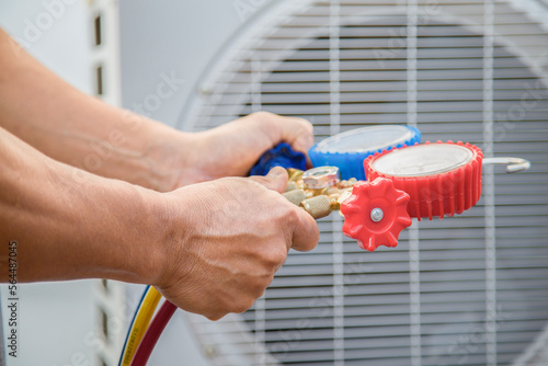 Air conditioning, HVAC service technician using gauges to check refrigerant and add refrigerant. photo