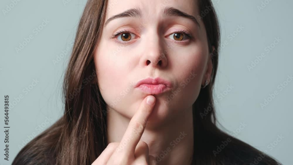 Virus herpes on lips close-up. Unhappy woman points to the painful swollen lips. Portrait of young beautiful girl European appearance with infection injury. Dermatology sickness. Facing treatment. 4K. Virus herpes on lips close-up. Unhappy woman points to the painful swollen lips. Portrait of young beautiful girl European appearance with infection injury. Dermatology sickness. Facing treatment. 4K.