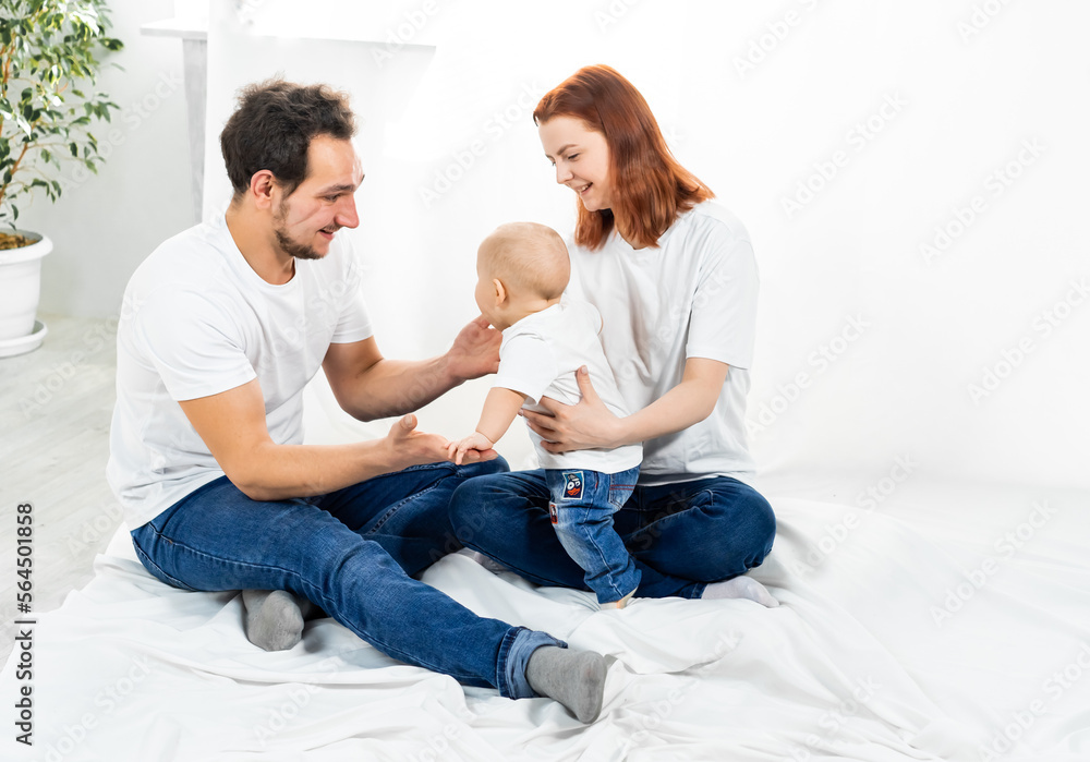 mom and dad sit on the floor and play with the baby. a happy family. family in studio or at home mom and dad sit on the floor and play with the baby. a happy family. family in studio or at home