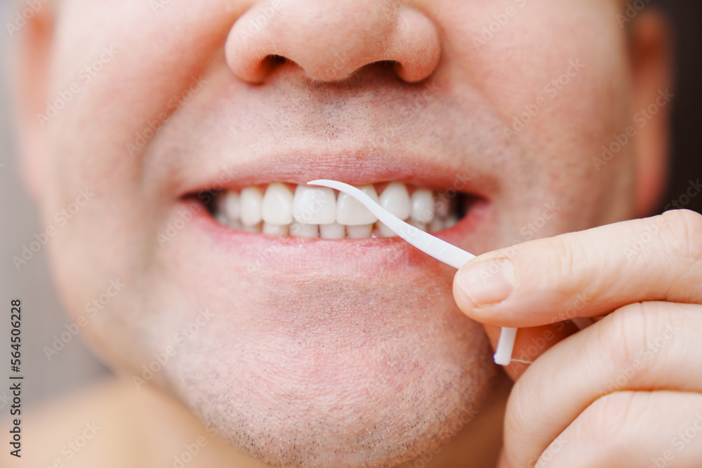 Naklejka premium a man's mouth close-up. a man brush your teeth plastic toothpick with dental floss. concept of hygiene and health of teeth and oral cavity. daily care and brushing of teeth.