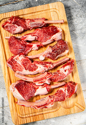 Cut into pieces of raw rack lamb on a cutting board. 