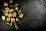 Pieces of kiwi with leaves on a cutting board. 