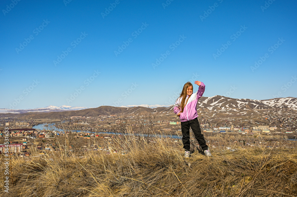 A teenage girl walks through the mountains. Happy young girl in a jacket in the wind. A walk in the fresh air. A teenage girl walks through the mountains. Happy young girl in a jacket in the wind. A walk in the fresh air.
