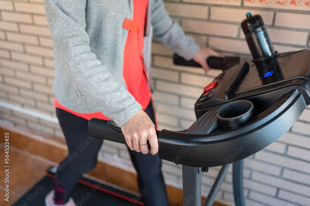 Senior white woman doing sports on a treadmill to walk at home and stay in shape. Senior white woman doing sports on a treadmill to walk at home and stay in shape.