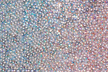 Abstract rhinestones background. Texture of rhinestones illuminated with multi-colored light. Pink and blue shine diamonds. Close up. Flares on glass