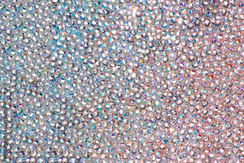 Abstract rhinestones background. Texture of rhinestones illuminated with multi-colored light. Pink and blue shine diamonds. Close up. Flares on glass