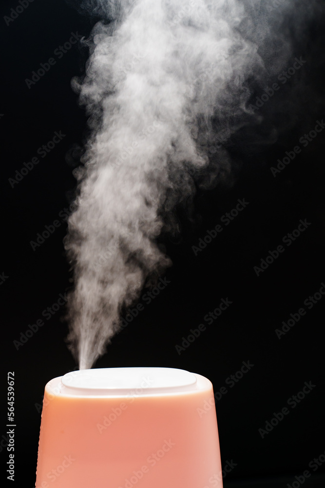 Steam from pink humidifier on a black background. Steam from pink humidifier on a black background.