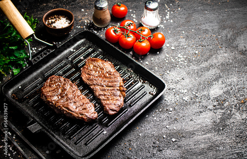 Grilled steak in a frying pan with tomatoes and spices.