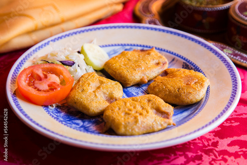 Samosa is a fried or baked dumpling with savory filling, such as seasoned potatoes, onions, peas, meat, or lentils.