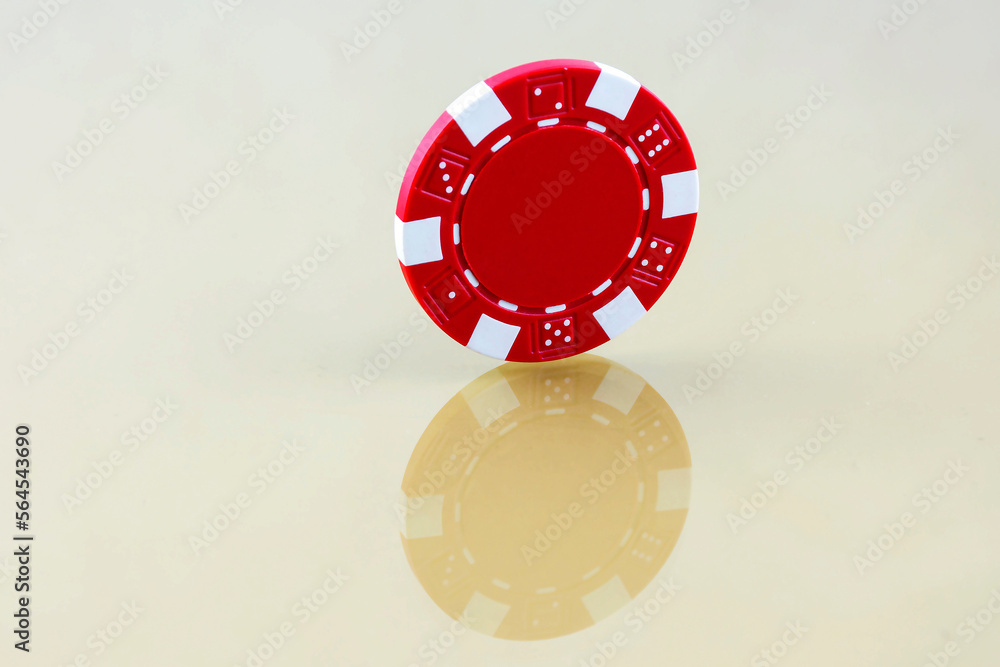 Red casino chip is worth an edge on the reflective surface Red casino chip is worth an edge on the reflective surface