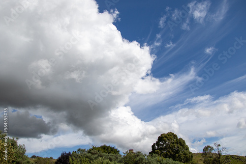 Clouds blown by the wind through a blue sky above a green countryside © Richard