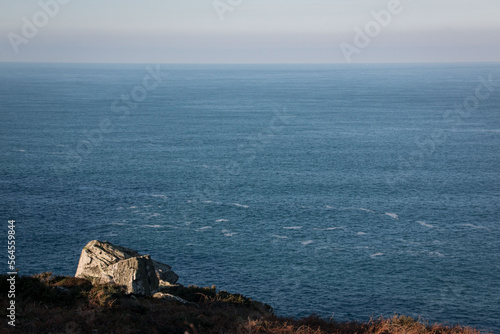 Light on rocks on cliff edge in corner with sea and sky behind, lots of space for copy