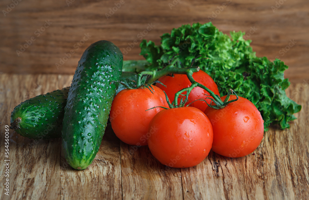 A few red tomatoes and cucumbers over a wooden background. Fresh vegetables. A few red tomatoes and cucumbers over a wooden background. Fresh vegetables.