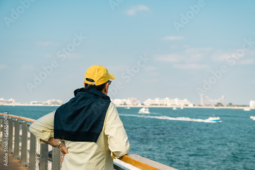 Senior man looks at the sea while walking along the promenade next to the marina