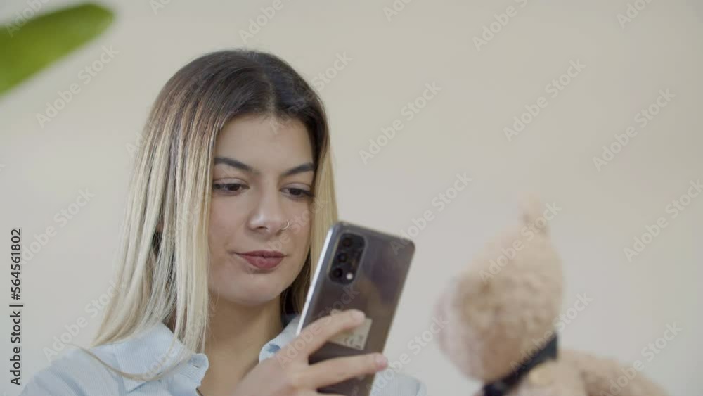 Young lady taking picture of teddy bear toy using her smartphone. Closeup shot of pretty Caucasian woman holding soft toy and shooting commercial video. Photography, hobby, startup concept Young lady taking picture of teddy bear toy using her smartphone. Closeup shot of pretty Caucasian woman holding soft toy and shooting commercial video. Photography, hobby, startup concept