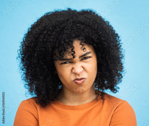 Black woman, portrait or angry facial expression on isolated blue background in mental health burnout. Headshot, model or person with mad, annoyed or frustrated face on backdrop mockup with afro hair © Alexis S/peopleimages.com