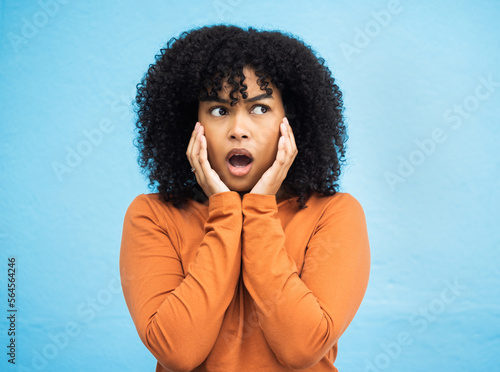 Wow, surprise and idea with a black woman in shock standing on a blue background in studio. Omg, confused and thinking with an attractive young female looking shocked or surprised indoor