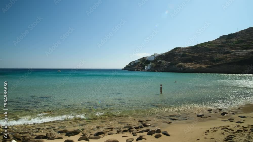 Close up view of a pile of stones, also known as cairn and a female tourist enjoying the beautiful beach of Kolitsani in Ios Greece Close up view of a pile of stones, also known as cairn and a female tourist enjoying the beautiful beach of Kolitsani in Ios Greece