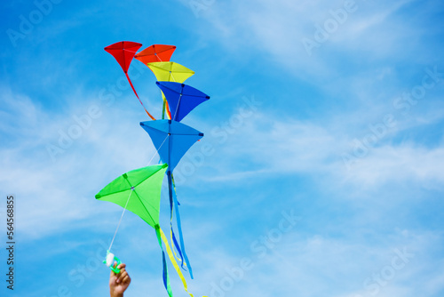 Close-up of a hand holding kites group over blue sky