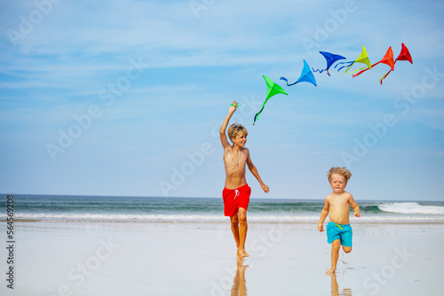 Two happy kids, boys run holding many colorful kites