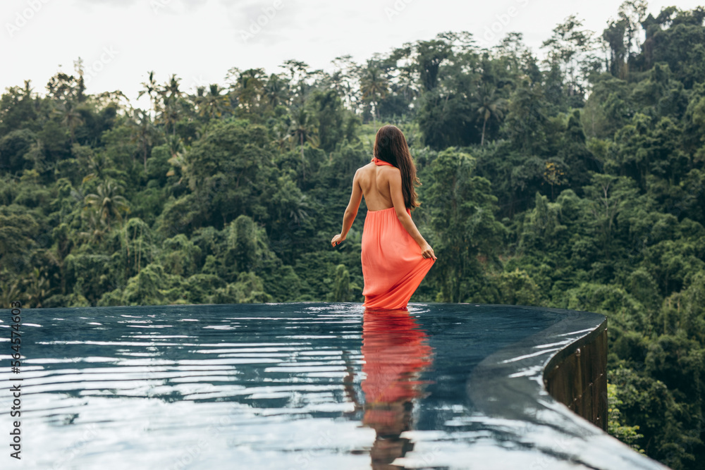 Fototapeta premium Female standing in swimming pool at luxury resort