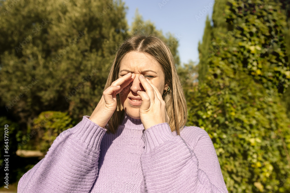 Close-up view of a woman scratching her eyes at the park Close-up view of a woman scratching her eyes at the park