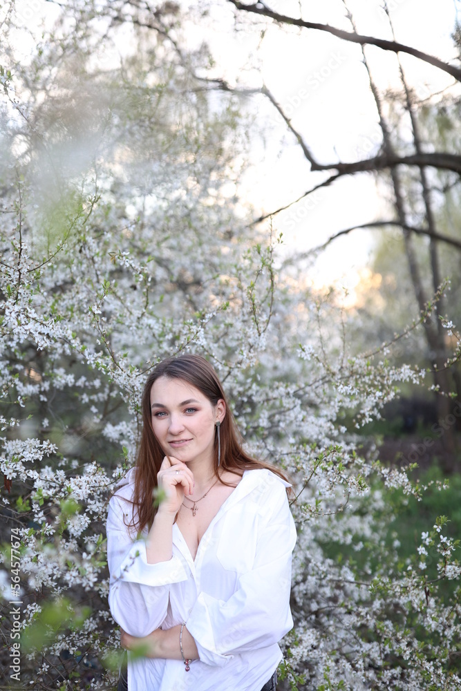 beautiful girl in a white shirt near a blooming tree. Beautiful warm spring and blossoming trees beautiful girl in a white shirt near a blooming tree. Beautiful warm spring and blossoming trees